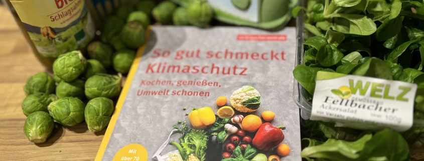 Cover des Buches „So gut schmeckt Klimaschutz“ mit verschiedenen Lebensmitteln im Bild